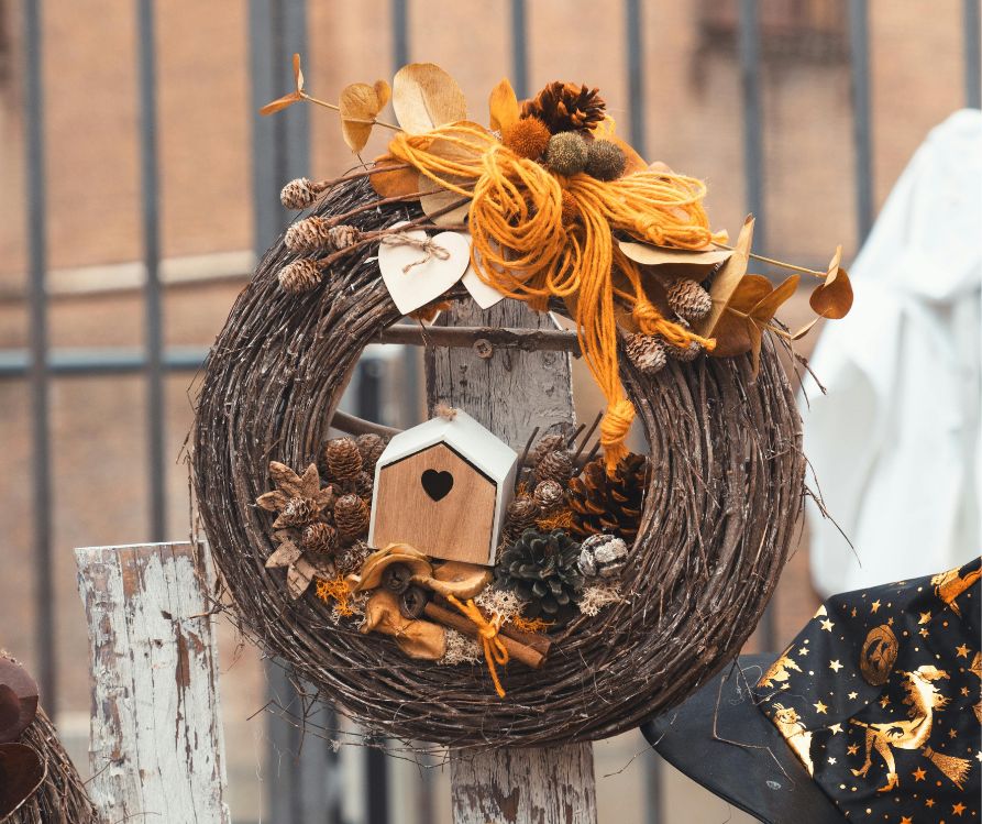 A nature inspired DIY fall wreath. Decorated with pinecones, leaves, a bird house, and yarn.