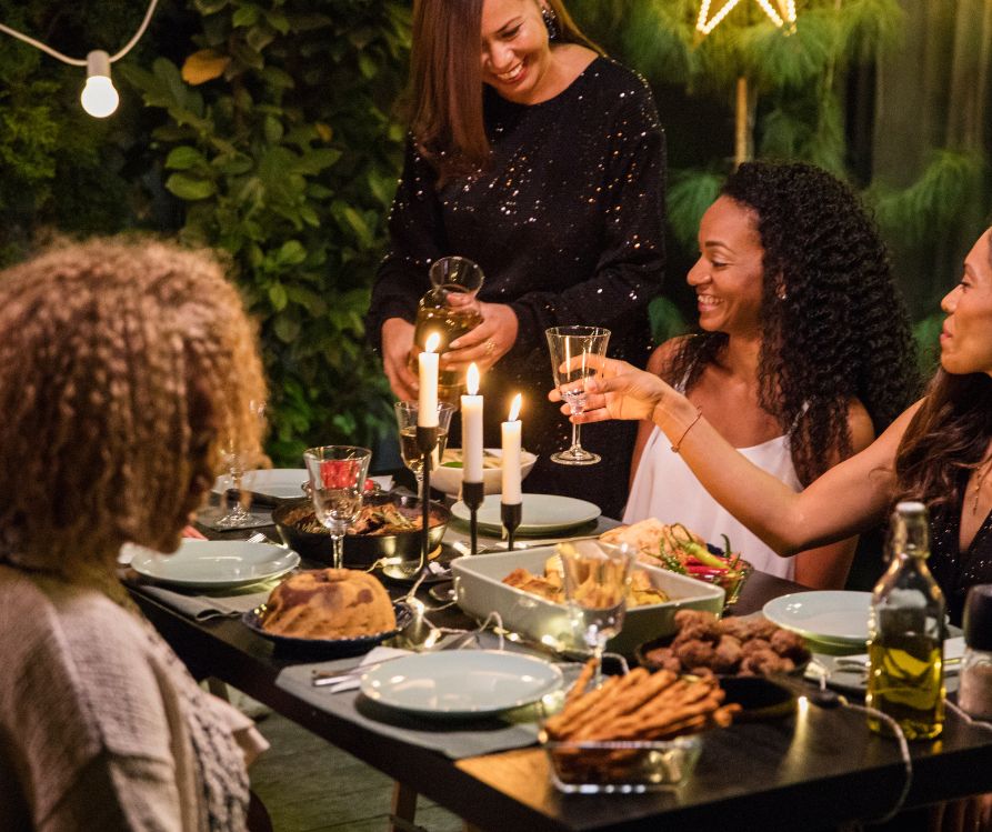 Women gathered around an outdoor dinner table enjoying themselves.