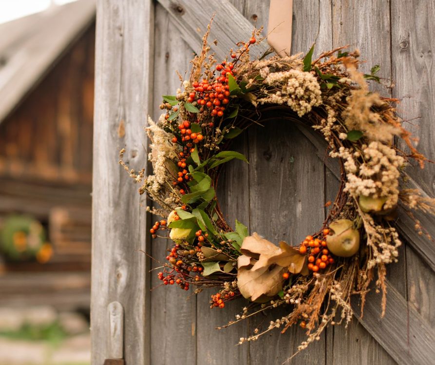 A wreath of dried vegetation and berried on a worn wooden door.