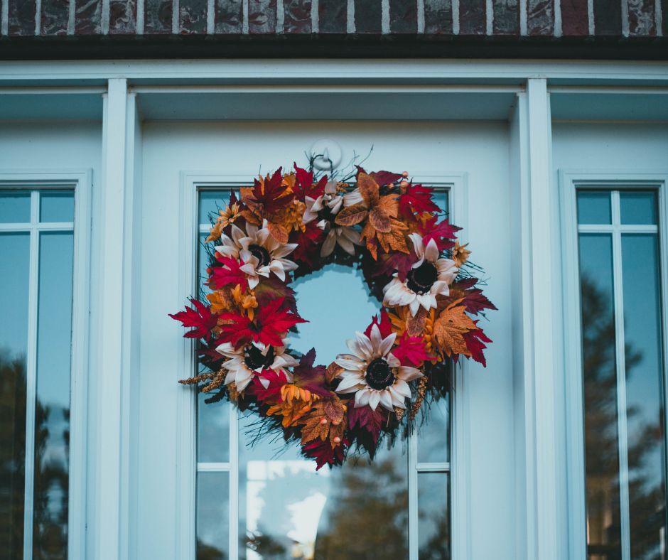A front door wreath made of flowers and fall leaves.