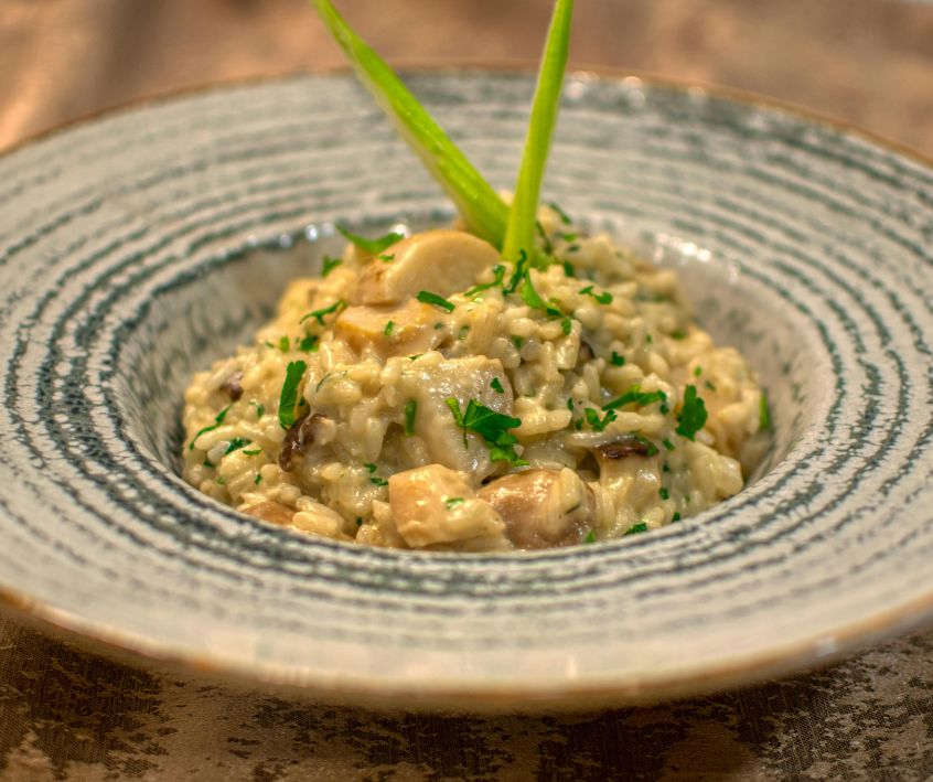 A ceramic bowl of risotto on a wooden table.