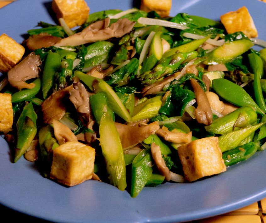 A blue plate of mixed vegetable, mushroom, tofu stirfry.