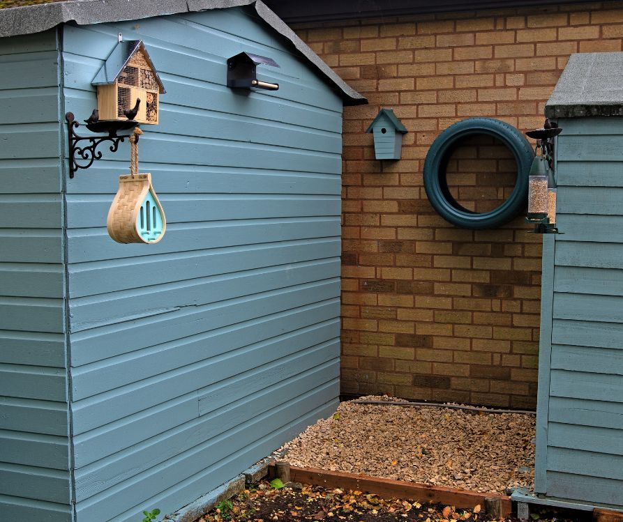 Bird house, insect shelters, and a bird feeder mounted on garden sheds.