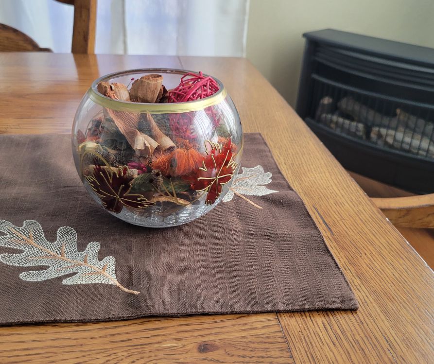A glass bowl of potpourri on table next to a wood stove.