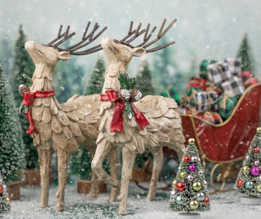 Christmas center piece made of two whimsical wooden reindeer pulling a sleigh on faux snow.