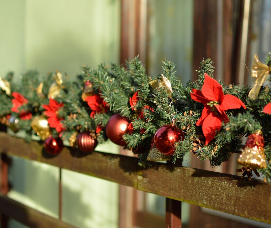 A evergreen garland decorated with red holiday accents.