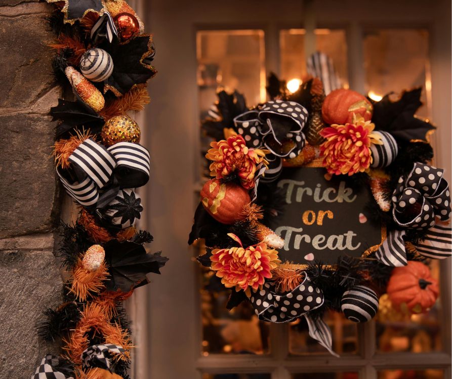 A door outlined in Halloween decorations and a wreath in black and orange. A sign reads "Trick or Treat" in whimsical font.