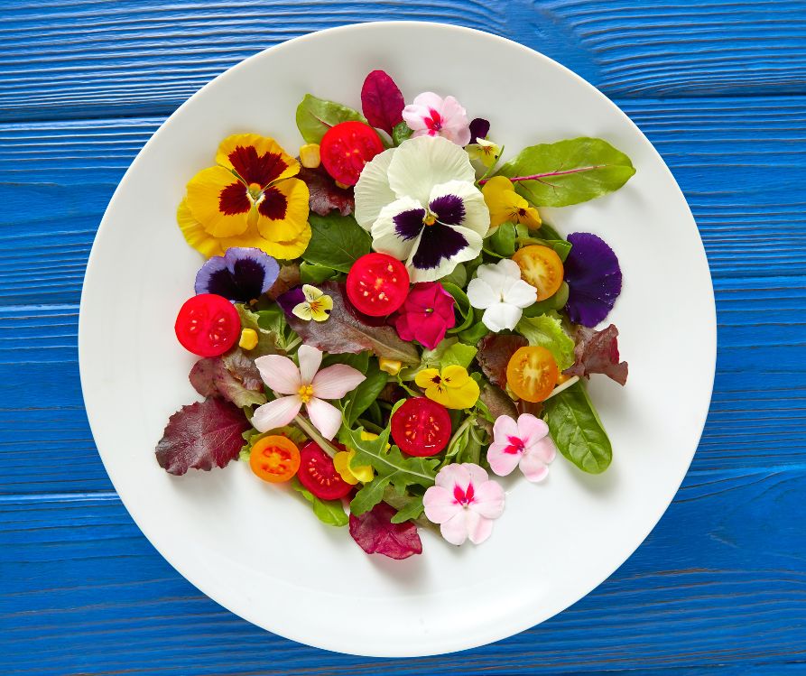 A fresh salad adorned with brightly colored edible flowers.