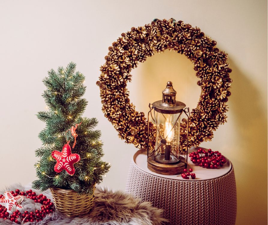 A pinecone wreath, lantern, and mini Christmas tree.