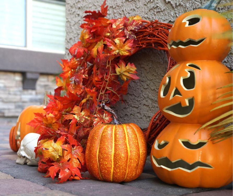 A bright fall leaf wreath next to orange jack o lantern figurines.