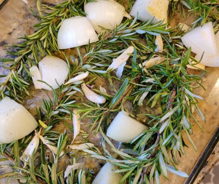 Rosemary, onions, and garlic in a glass baking dish.
