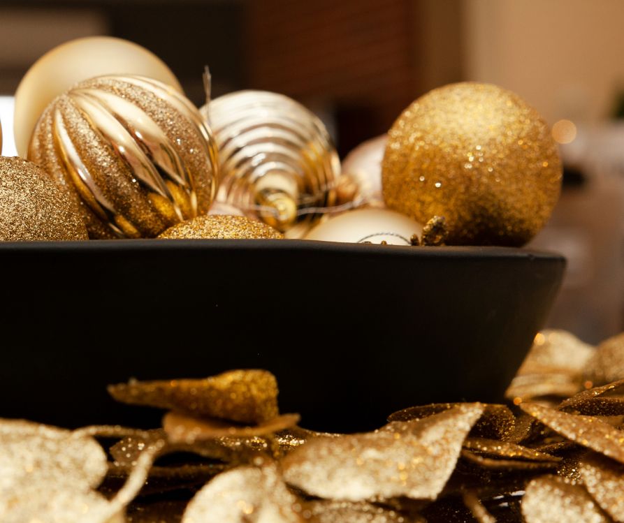 A bowl of metallic ornaments and glitter and metallic gold painted garlands. 