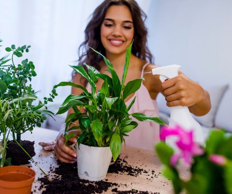 A woman misting potted indoor plants.