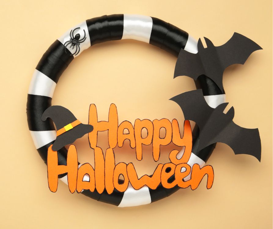 Black and white striped wreath with "Happy Halloween" in orange cut out letters and two black bats.