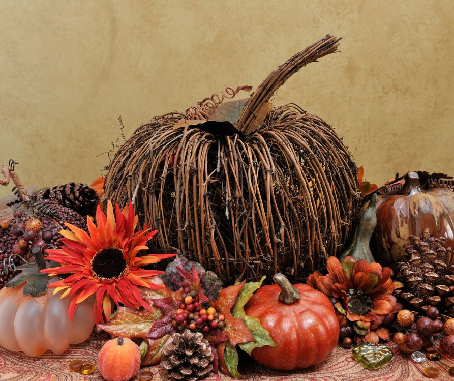 A wicker pumpkin, warm hue flowers and small gourds.
