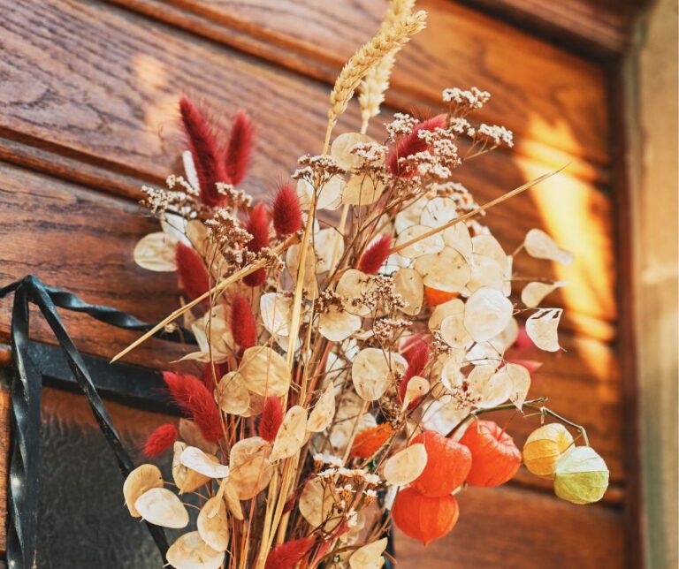 A sprig of dried fall foliage and flowers attached to a door.