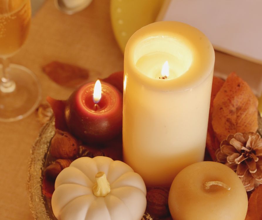 Three warmly colored candles and mini pumpkins as a table centerpiece.