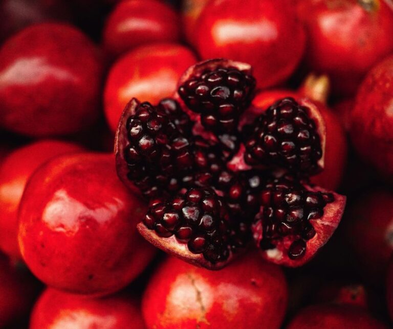 Pomegranate fruit opened to reveal dark red seeds.