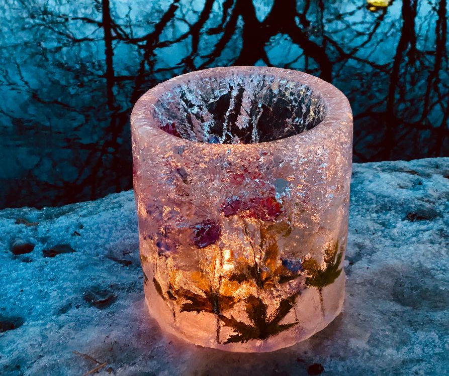A homemade ice lantern with winter leaves and berries imbeds.