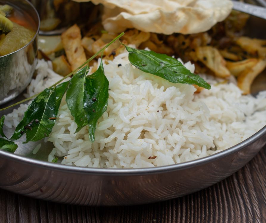 South Indian masoori rice dish with a tempered curry leaf twig on it