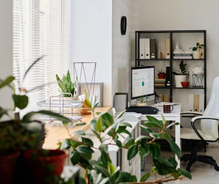 A refreshing home office with a desk facing a bright window and indoor plants incorporated in the decorations.