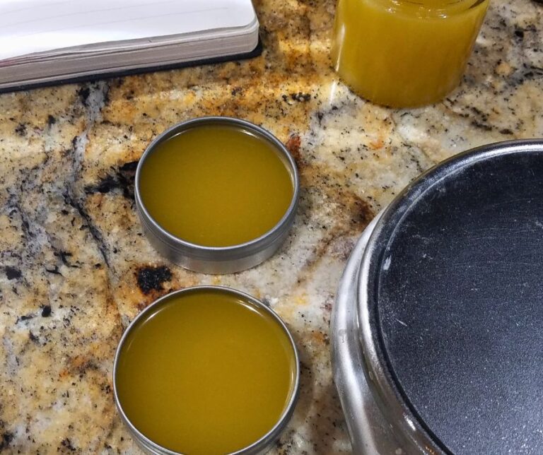 Two tins and one glass jar of homemade body butter next to a kitchen scale.
