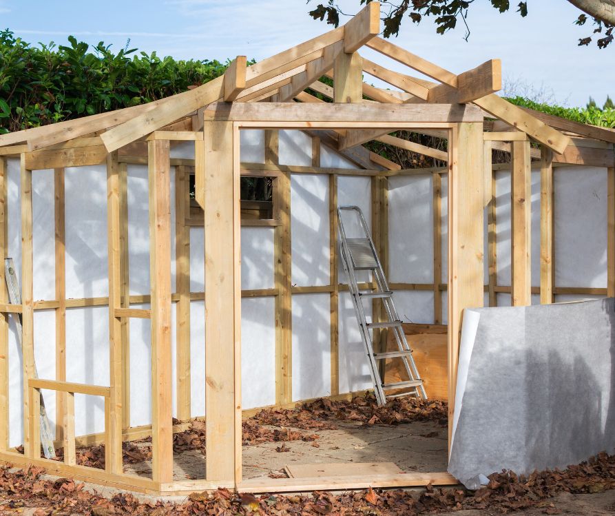A backyard greenhouse in the process of being built. the shaded side is insulated.