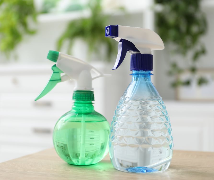 One green and one blue transparent spray bottles.