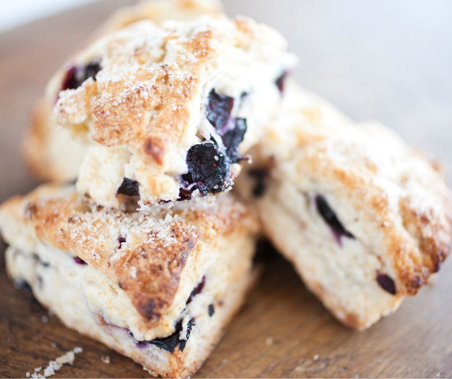 Three wedge shaped blueberry scones on a wooden platter.