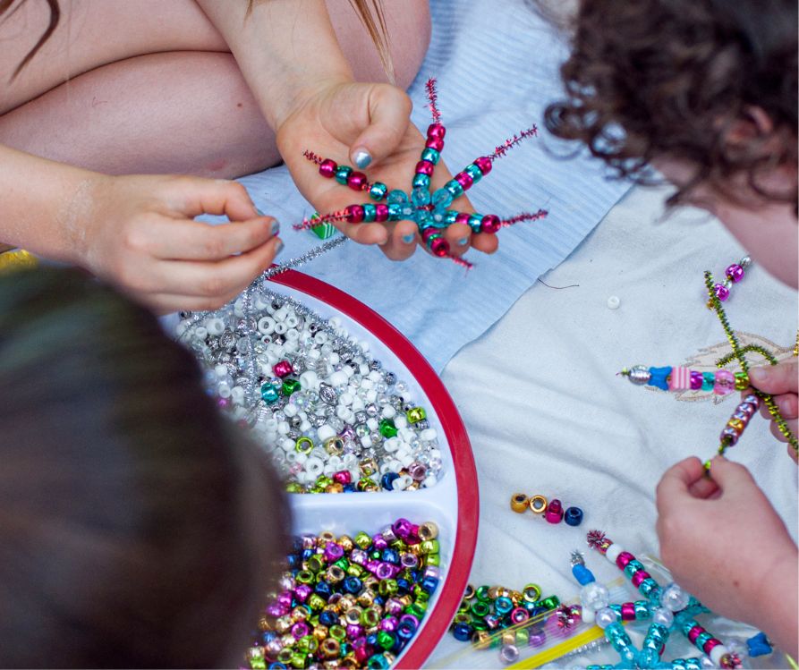 Kids making brightly colored beaded snowflakes.