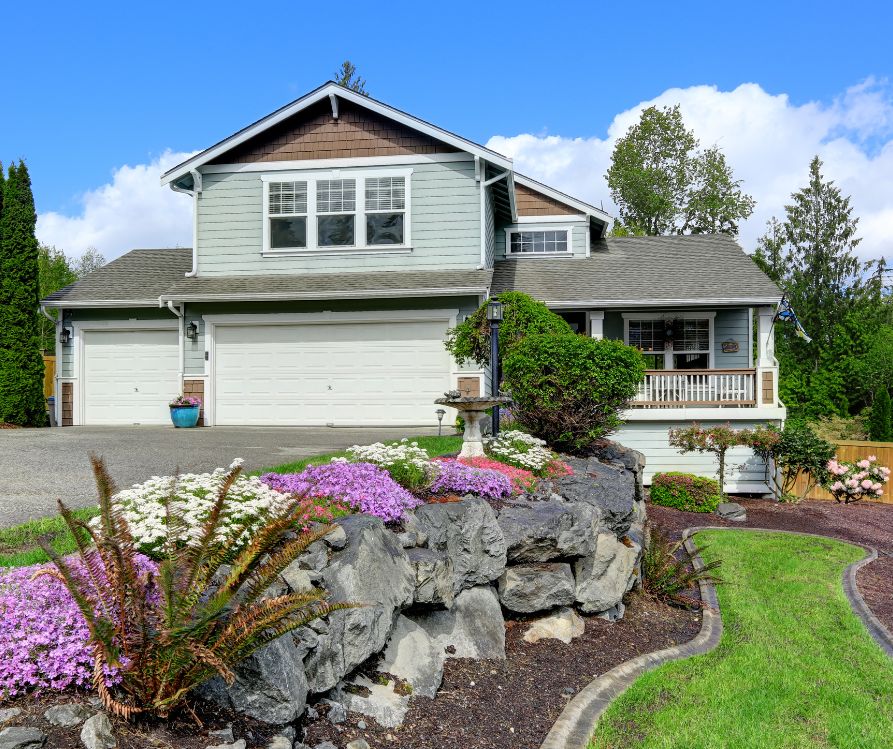 House exterior with curb appeal. View of stone wall, porch, and garage.