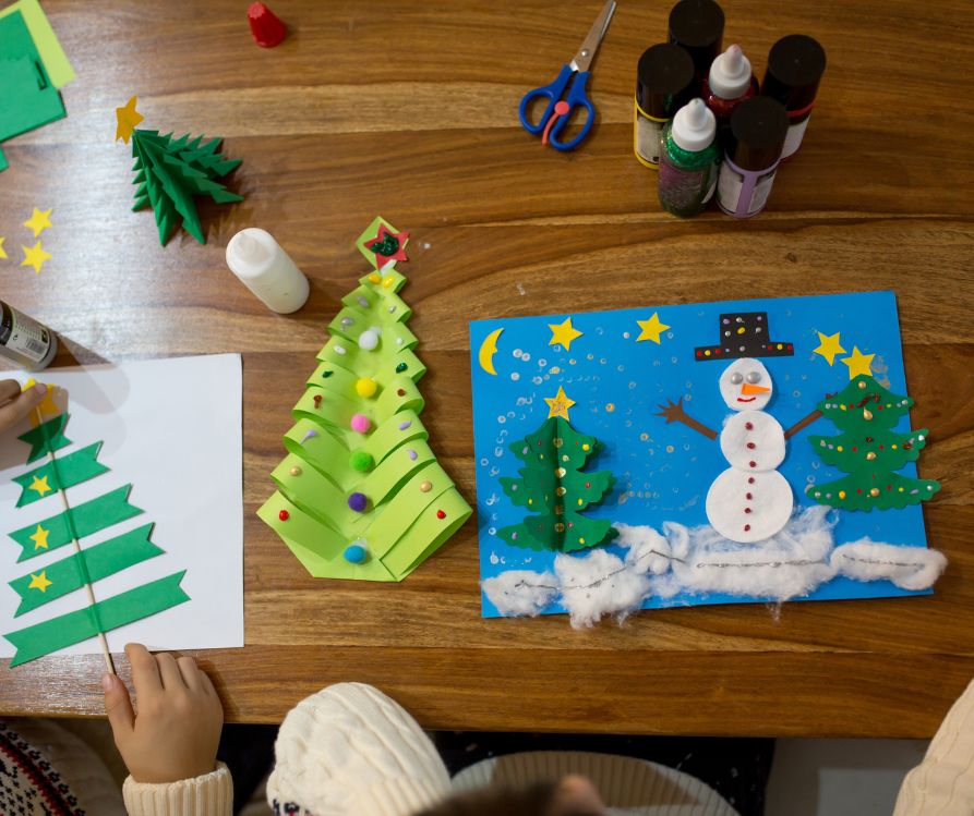 A winter collage make of a variety of materials featuring a snowman and Christmas tree.