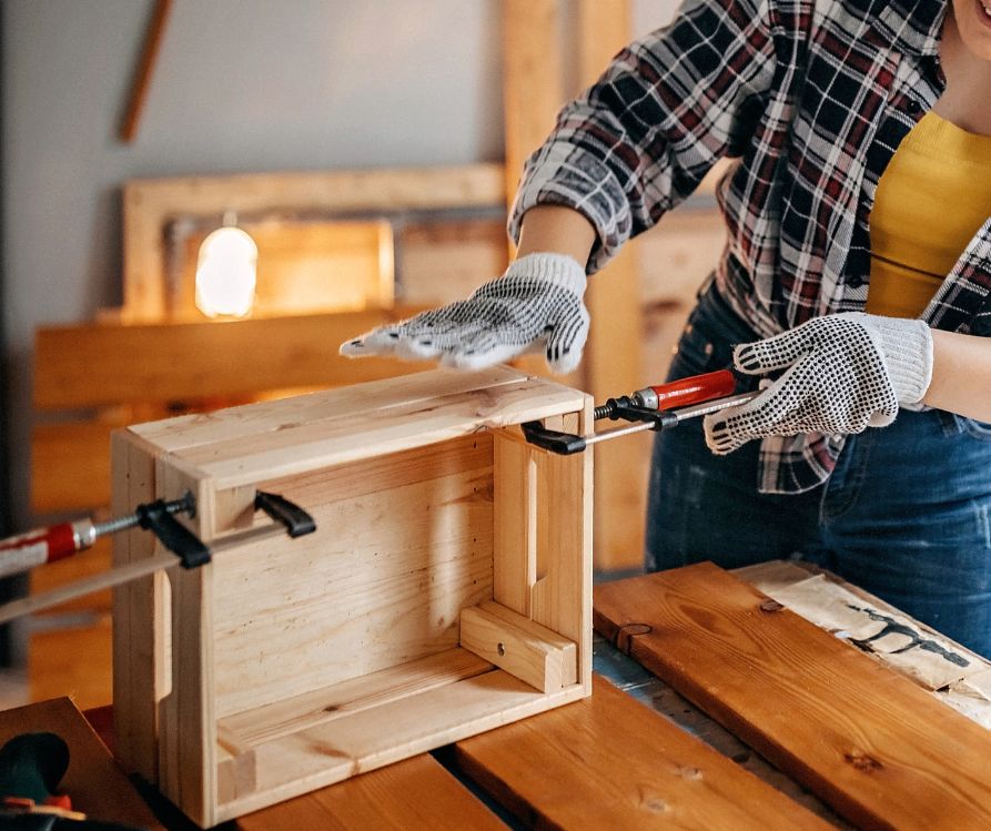 A woman building a wooden piece of furniture.
