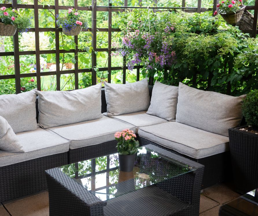 A comfy private patio with a lot of potted plants and a sectional sofa.
