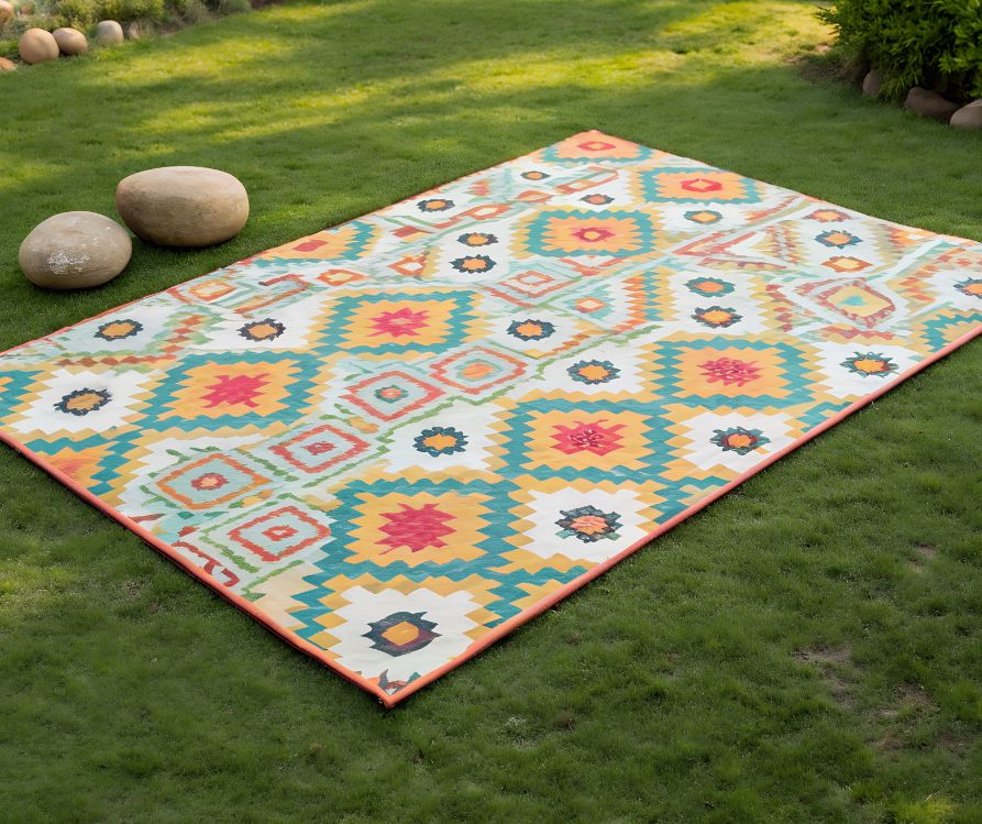 Colorful geometric outdoor rug on green grass.