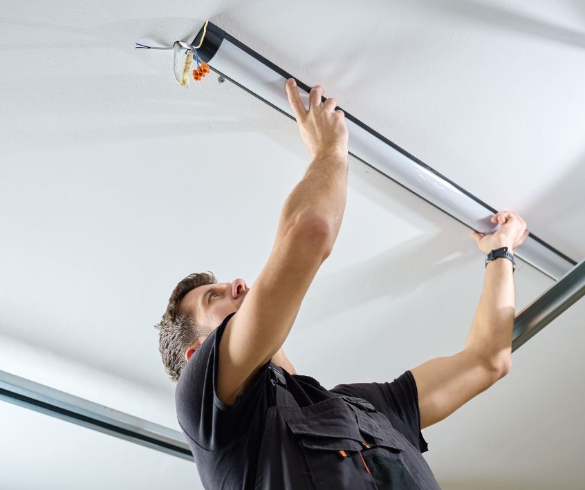A man installing fluorescent tube light fixture in garage.