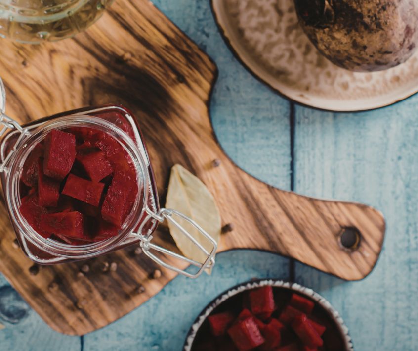 Overhead view of cubed pickled beets and other preserves on a wooden board.