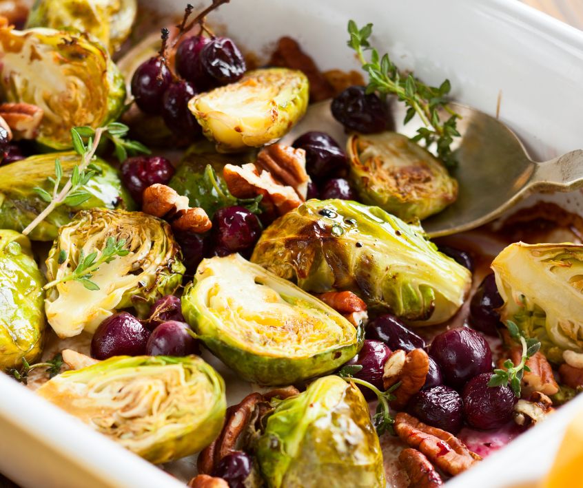 Roasted Brussels Sprouts, cranberries, and thyme in a ceramic pan.