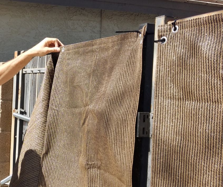 A person applying fabric privacy screen to a gate with zip ties.