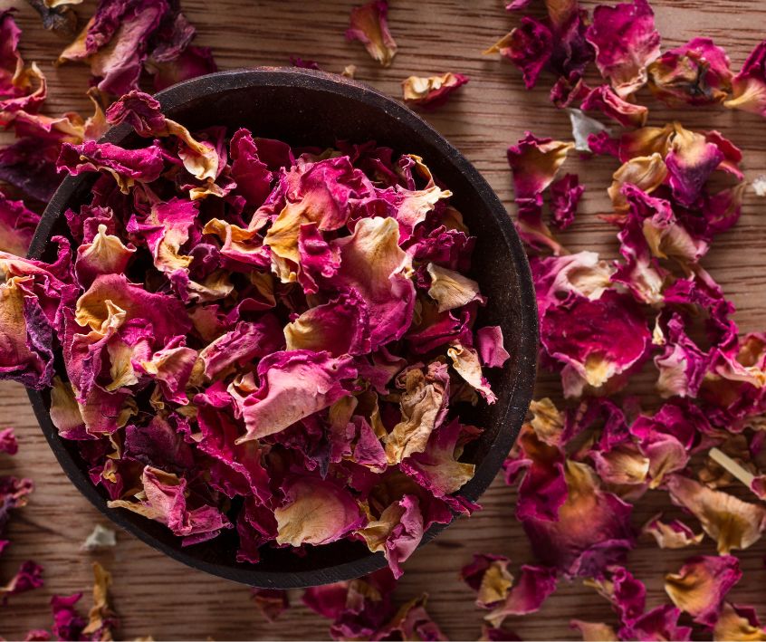 Dried red rose petal in a dark bowl and surround table top.