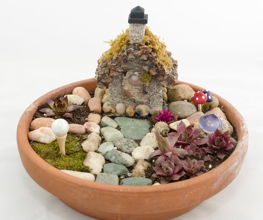 Fairy Garden in a Terra Cotta Saucer. Including a small house, green moss lawn and a pebble walkway.