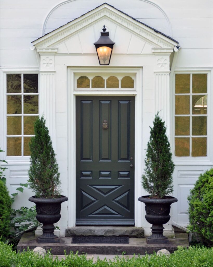 Two large planters framing a dark front door.