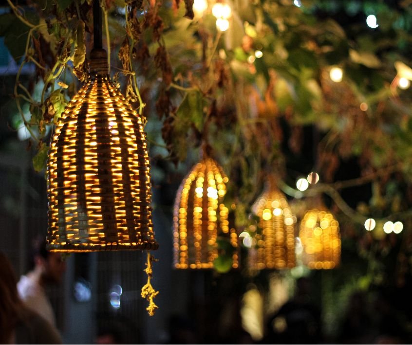 Woven basket lights and strings lights decorating a small garden.