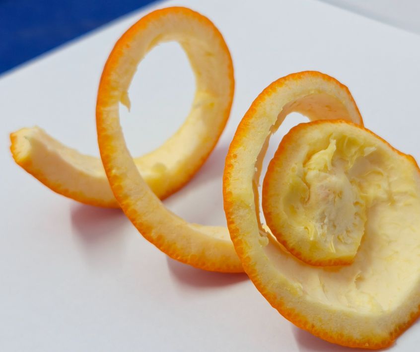 An orange peel swirl on a white cutting board.
