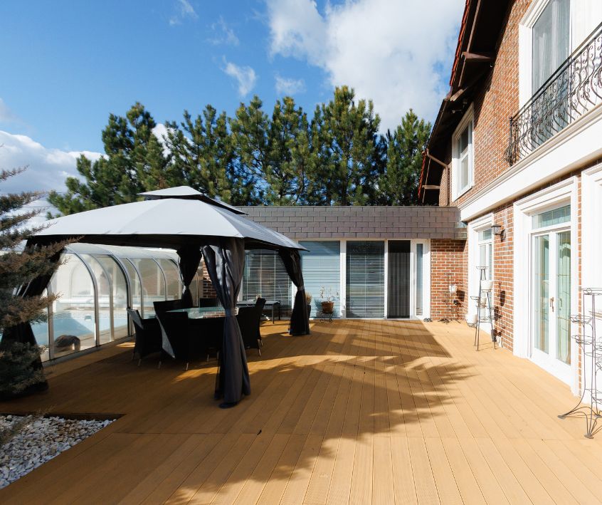 Modern deck with a gazebo shaded sitting area next to a covered pool.