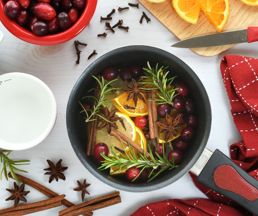 A blend on rosemary, citrus, and spices in a pot on a counter surrounded by ingredients.