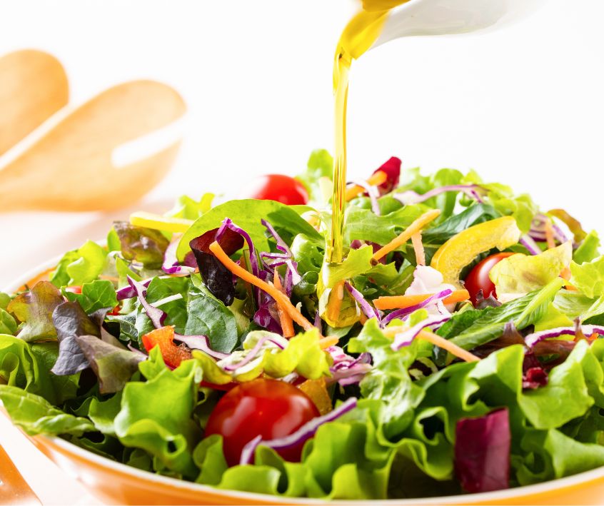 Homemade dressing being poured over a fresh summer salad.