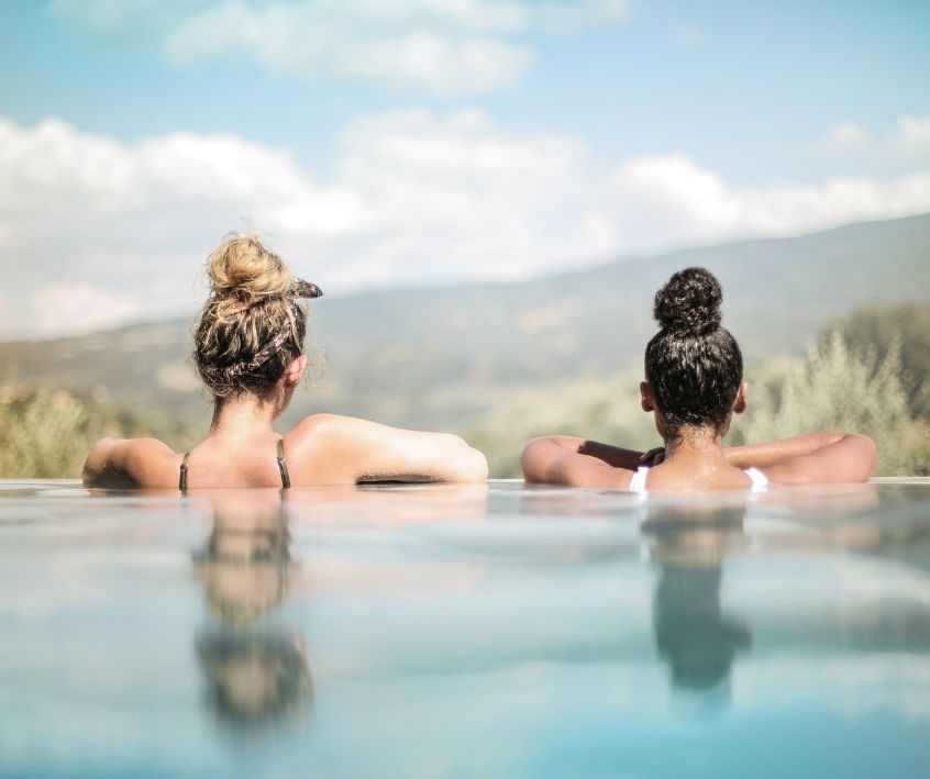 Two women looking over the edge of an infinity pool on a sunny day.