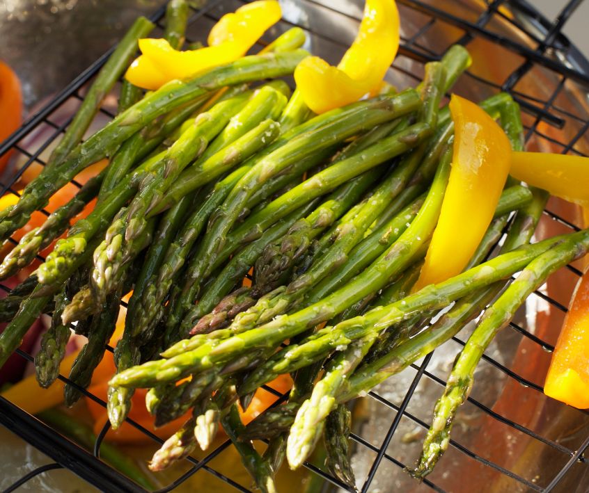 Asparagus and sliced yellow bell pepper in grill basket.