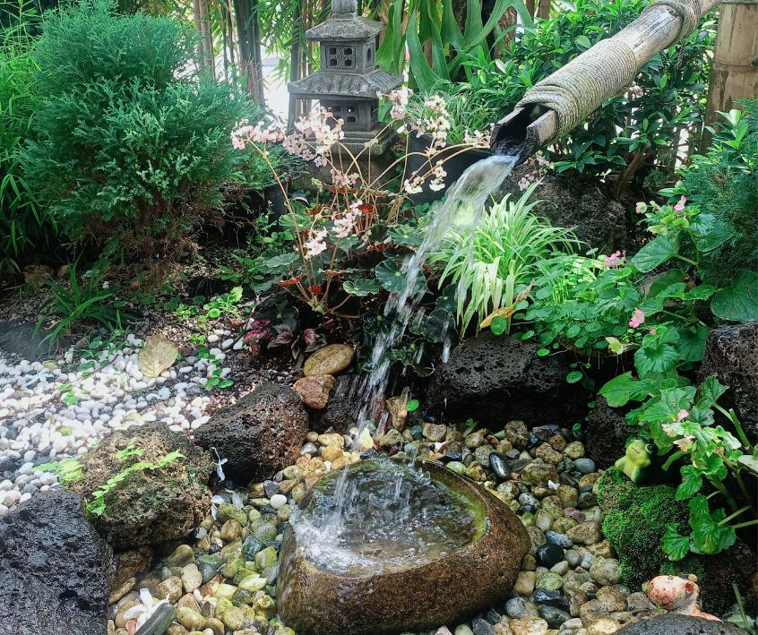 Japanese style backyard garden water feature with bamboo spout.
